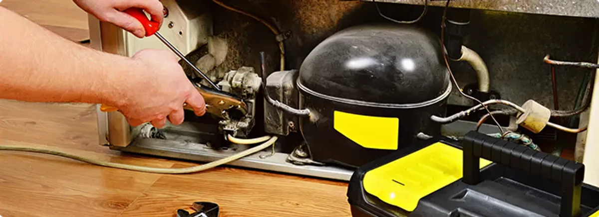 Refrigerator repair technician fixing the compressor and wiring in Kennedale, TX