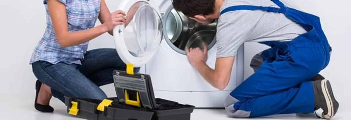Washer repair technician inspecting a front-load washing machine with tools in Arlington, TX