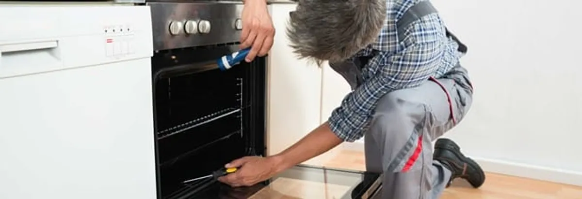 Oven repair technician inspecting and servicing an electric oven in Arlington, TX